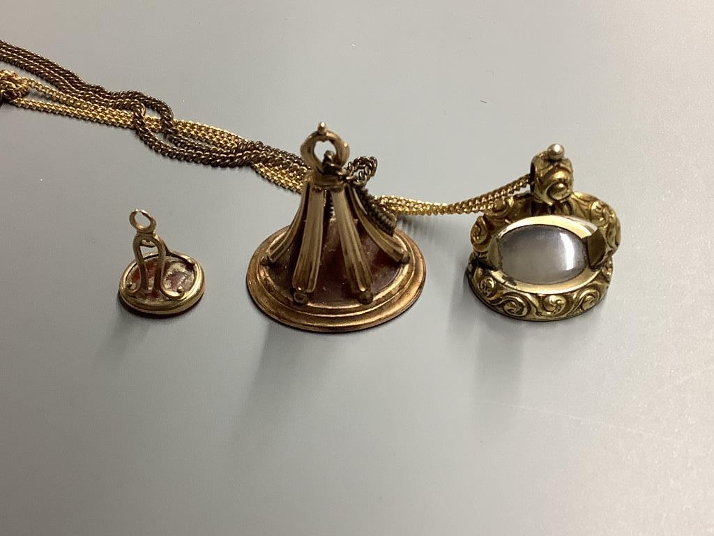 Three assorted 19th century yellow metal overlaid and carnelian set fob seals, two on gilt metal chains, largest 41 mm.